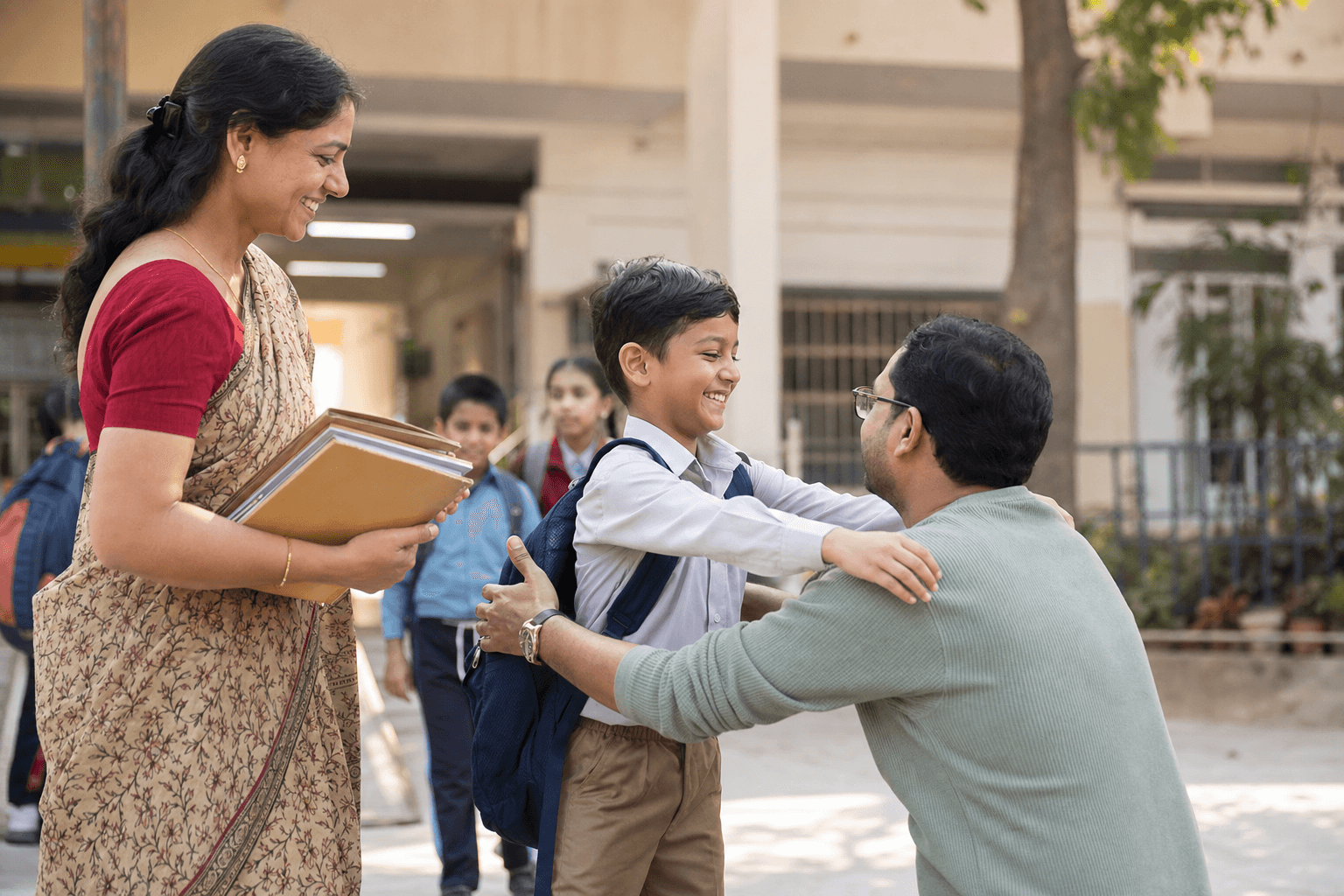 An Indian child reunites with a parent while a teacher supervises outside school.